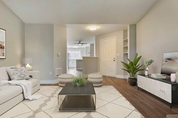 A living room with a white couch, a coffee table, and a plant at The Village at Seeley Lake Apartments, Lakewood, WA 98499
